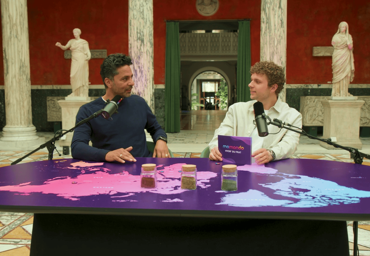 Two Hvor' du fra? hosts in conversation at the campaign table